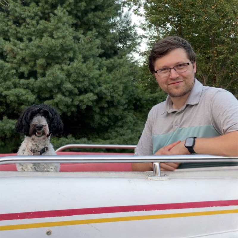 Co-founder James sitting on a boat with his dog outdoors